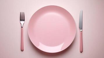 Pink empty dinner plate with fork and knife in overhead view photo