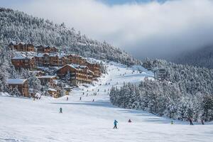 A ski resort with people skiing down the mountain photo