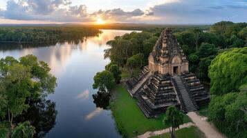 Ancient temple by serene river at sunset, surrounded by lush greenery photo