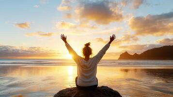 woman sitting on rock at beach, enjoying sunset view photo