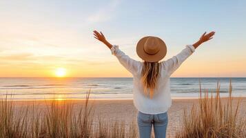 Silhouette of woman with beach hat enjoying sunset by ocean photo