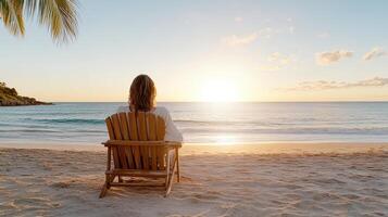 Relaxing woman on beach chair watching sunset over ocean waves photo