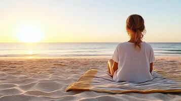 Relaxing woman on beach towel watching sunset over ocean photo