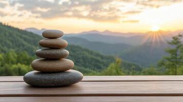 Serene stacked stones on wooden surface with mountain sunset backdrop photo