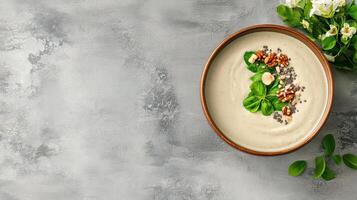Creamy green smoothie bowl topped with nuts and fresh leaves photo