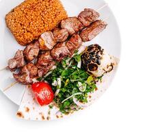 Savory grilled meat skewers with bulgur and fresh vegetables photo