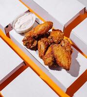 Crispy chicken wings with creamy dip on a colorful backdrop photo