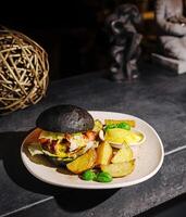 Gourmet black bun burger served with golden fries and dipping sauce photo