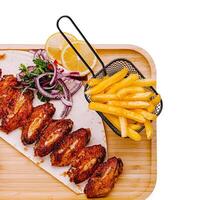 Crispy chicken wings served with fries and fresh lemon slices photo