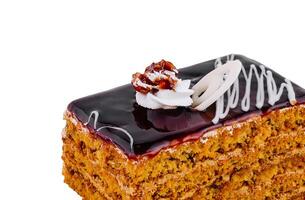 Delicious honey cake layered with chocolate glaze and topped with walnut and whipped cream closeup photo