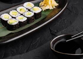 Avocado sushi roll with soy sauce on slate background photo