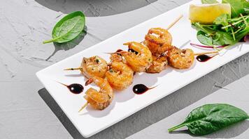 Shrimp skewers served with salad and lemon on a white plate photo