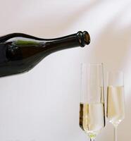 Pouring sparkling wine into elegant flute glasses photo