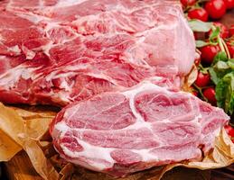 Fresh cuts of pork resting on butcher paper with tomatoes photo
