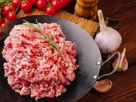 Freshly minced meat on a rustic kitchen counter with herbs photo