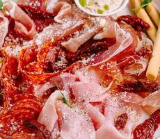 Assorted deli meats platter with dips and breadsticks closeup photo