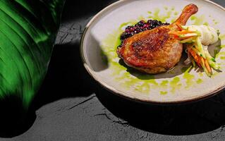 Crispy duck leg served with berry sauce and fresh vegetables photo