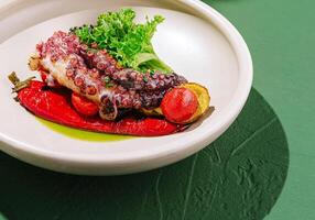 Grilled octopus dish presented with vibrant vegetables and greens photo