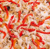 Delicious fresh pizza topped with chicken, red and yellow bell peppers, and mushrooms at a casual dining location photo