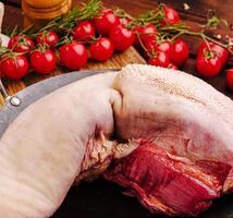 Fresh meats and vibrant tomatoes prepared on a rustic wooden table photo