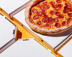 Freshly baked pepperoni pizza with empty boxes on a table photo