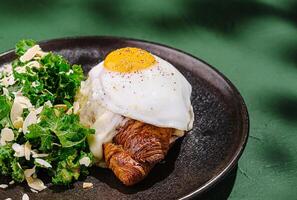 Delicious croissant topped with fried egg and greens on plate photo