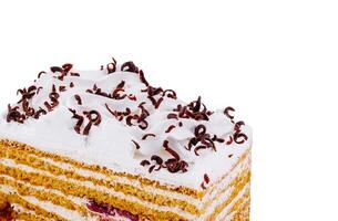 Delicious honey cake decorated with whipped cream and chocolate shavings close up photo