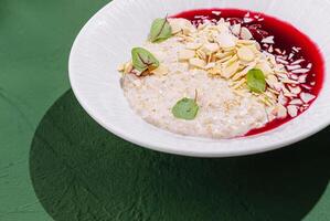 Delicious oatmeal bowl topped with berry sauce and almonds photo