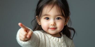 Child pointing with a cheerful expression while wearing a cozy sweater in a softly lit indoor setting photo