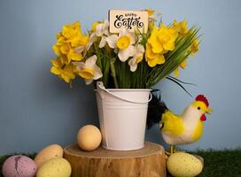 Yellow spring flowers in a white bucket on a wooden piece Easter eggs and chicken photo