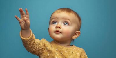 Baby reaching towards the ceiling in a playful moment against a bright blue backdrop during a sunny afternoon photo