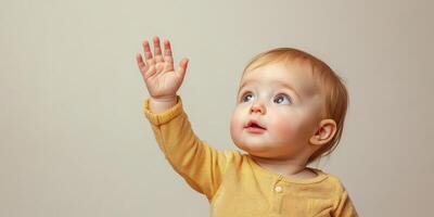 Baby joyfully reaches out with hand against a simple background during playtime at home photo