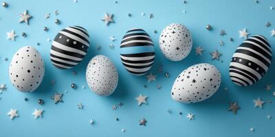 Unique black and white decorated eggs arranged on a blue background with stars and silver beads for a festive presentation photo