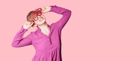 A beautiful young woman with festive New Year's joy, wearing Christmas glasses on a bright background with a place for text photo