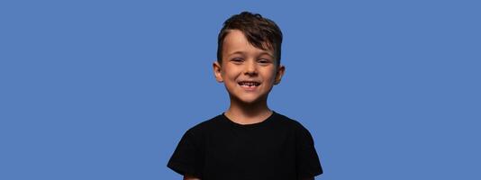 A charming boy is smiling without a tooth on a blue background. The boy lost his first baby tooth. copy space photo