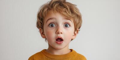Young child expresses surprise with wide eyes and open mouth in a neutral setting photo