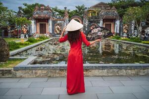 Young woman in red dress in front of Buddhist temple during Spring Festival, view from back photo