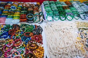 A collection of colorful, beaded bracelets and necklaces displayed at a market, featuring gemstones, pearls elements photo