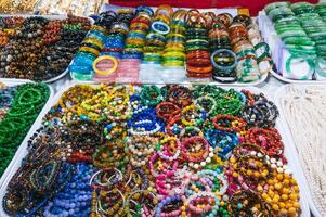 A collection of colorful, beaded bracelets and necklaces displayed at a market, featuring gemstones, pearls elements photo