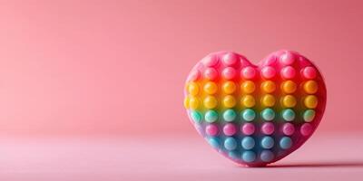 Colorful heart-shaped sensory toy sits against a pink backdrop showcasing rainbow hues and a playful design photo
