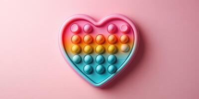 Heart-shaped pop it toy in vibrant colors resting on a pink background to create a cheerful aesthetic photo