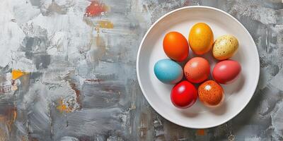 Colorful Easter eggs arranged in circular pattern on a white plate placed on a textured surface photo