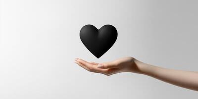 Black heart being held softly in an open hand against a minimalist background photo