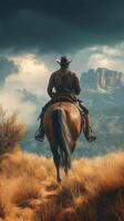 Man riding a horse on a rugged trail through golden grass under a dramatic sky in a mountainous area photo