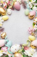 Easter eggs frame on a gray background with flowers and feathers photo
