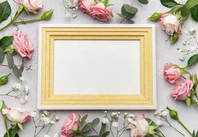 Empty frame surrounded by pink roses and eucalyptus on grey background photo