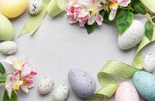 Easter eggs and spring flowers creating a frame on a gray background photo