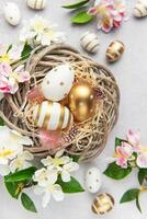 Easter eggs are lying in a nest with spring flowers on a gray background photo