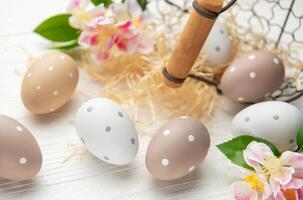 Easter eggs are decorating a white wooden table with raffia and flowers photo