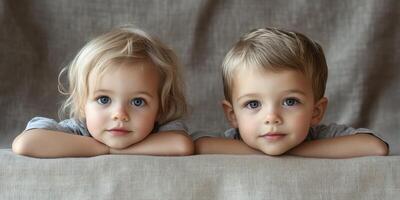 Two young children posing closely with their heads resting on a soft fabric during a cozy indoor moment photo
